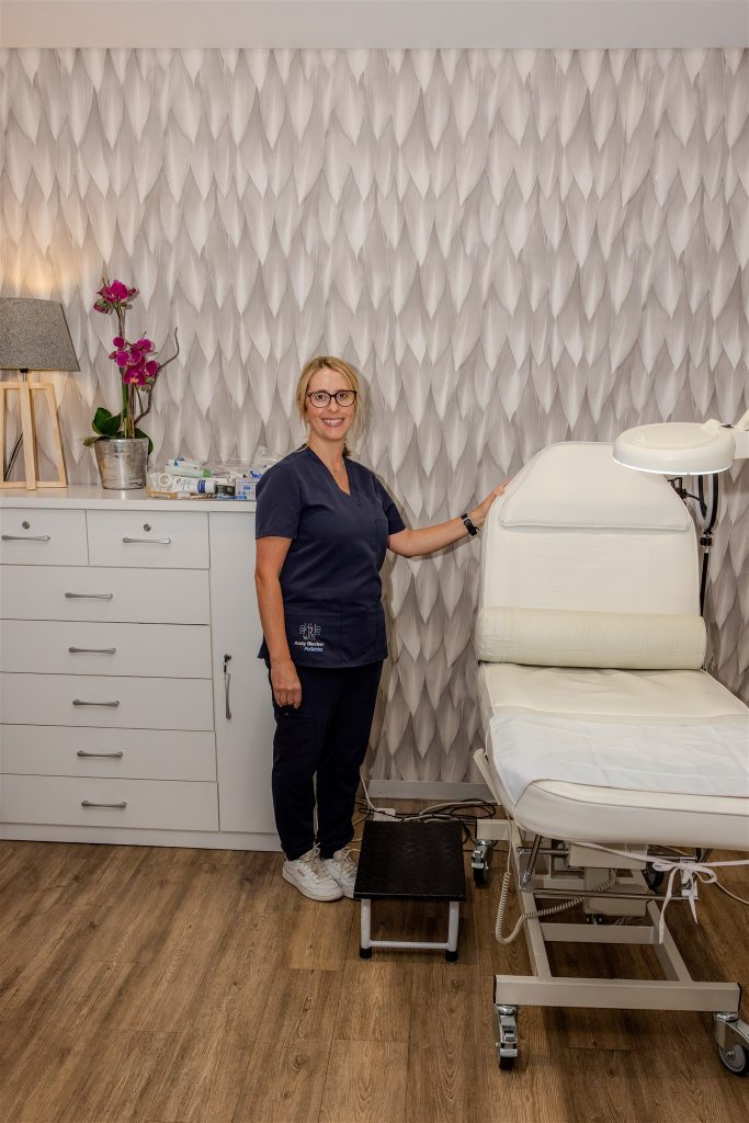 Andy Blecher, podiatrist, standing beside a treatment chair in a consulting room