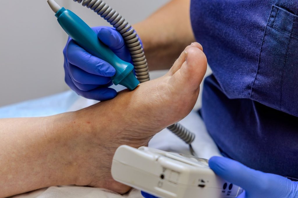 Podiatrist performing a vascular ultrasound examination on a patient's foot, close-up view
